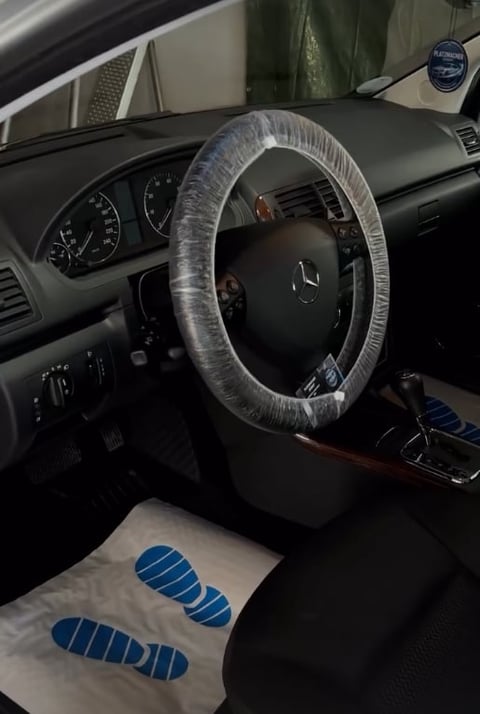 Car interior with steering wheel wrapped in clear plastic and protective coverings