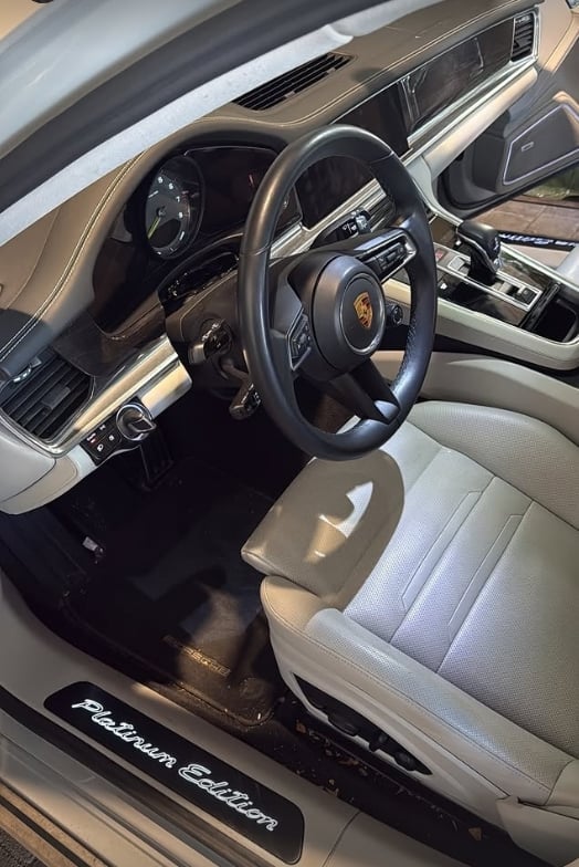 Luxury sports car interior with Porsche logo steering wheel and tan leather seats