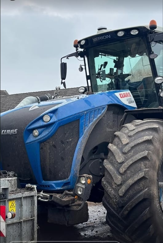 Blue and black CLAAS tractor with large treaded tires next to Xerion tractor