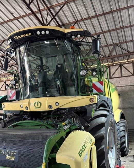 Krone combine harvester with yellow and green coloring parked in industrial hangar