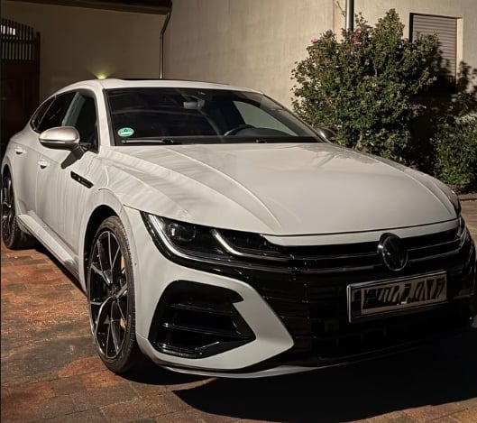 White Volkswagen Arteon sedan parked in driveway with modern LED headlights and alloy wheels