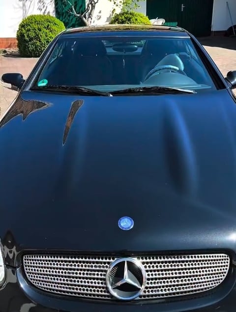 Front view of a black Mercedes-Benz car parked in a driveway